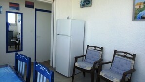En matplats med ett bord och stolar, ett kylskåp och två stolar som är monterade på väggen.