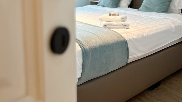 Un dormitorio con cama, almohadas y una mesita de noche.