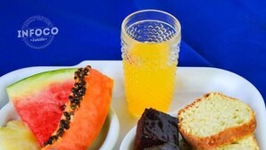 A tray with various food items including bread, jam, cheese, and a glass of orange juice. - Pousada Sossego (Buzios)