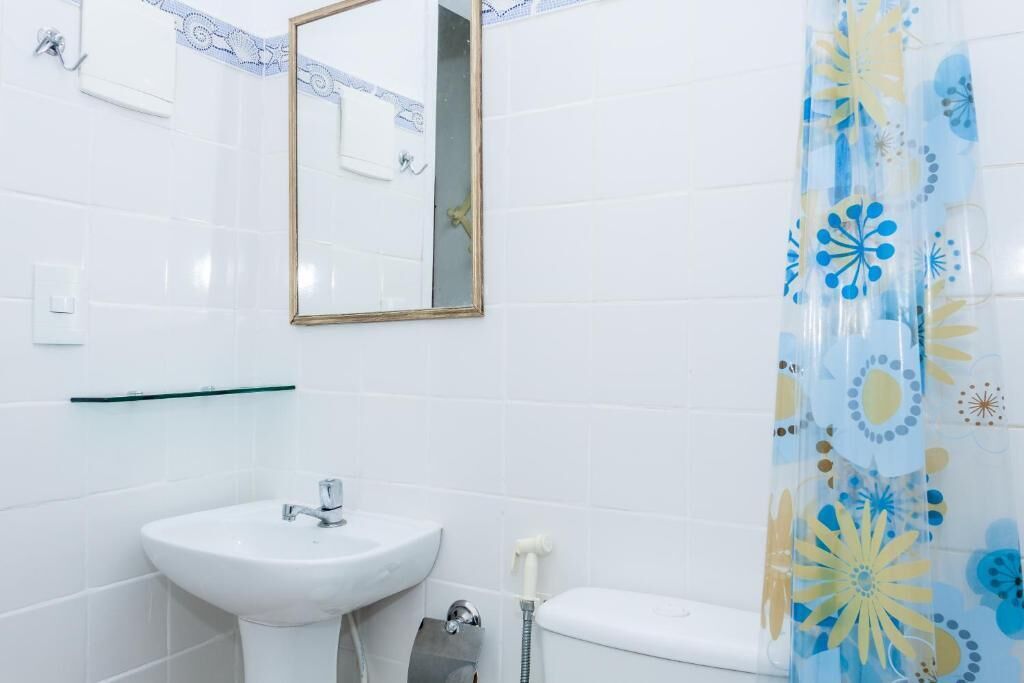A bathroom with a white sink, toilet, and a shower curtain with a floral pattern.