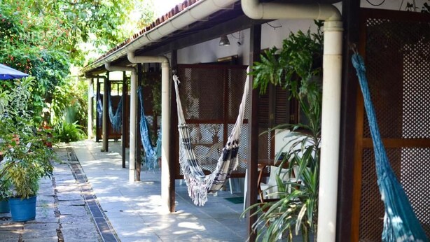 A covered outdoor area with hammocks, potted plants, and a tiled walkway. - Pousada Sossego (Buzios)