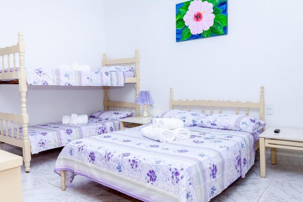 Una habitación con dos camas de madera, cada una con una colcha y almohadas a juego de estampado floral. Hay una mesita de noche con lámpara junto a cada cama.