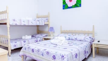 Una habitación con dos camas de madera, cada una con una colcha y almohadas a juego de estampado floral. Hay una mesita de noche con lámpara junto a cada cama.