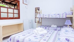A bedroom with two beds, a wooden headboard, a window with a view, and a bedside table. - Pousada Sossego (Buzios)
