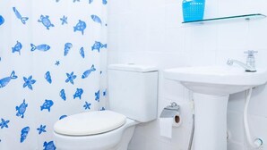 A bathroom with a toilet, sink, and a shower curtain with blue fish patterns. - Pousada Sossego (Buzios)