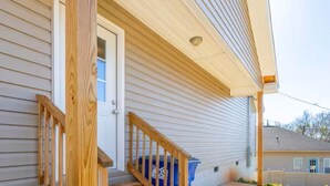 A house with a wooden staircase leading to a front door, a concrete driveway, and a garage door. - Oxford Cottage (Oxford)