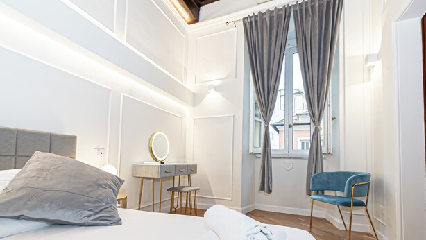 Ett hotellrum med en säng, ett skrivbord med en spegel, en stol och ett fönster med gardiner.