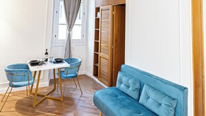 Ett rum med ett träpanelat tak, en blå soffa, ett matbord med stolar och en garderob.