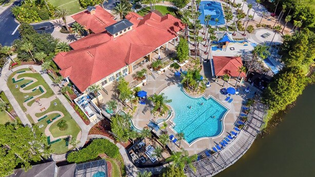 Luftaufnahme eines Resorts mit Schwimmbad, Tennisplätzen und einer Anlegestelle.