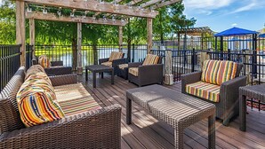 Eine überdachte Terrasse im Freien mit Korbmöbeln, einer Pergola und Blick auf ein Gewässer.