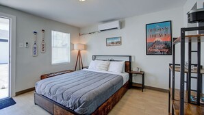 Een slaapkamer met een bed, nachtkastje, lamp en een poster aan de muur.