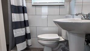 Een kleine badkamer met toilet, wastafel en douchegordijn.