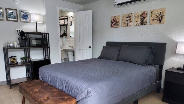 Een slaapkamer met een bed, een bankje, een plank met spullen en kunst aan de muur.