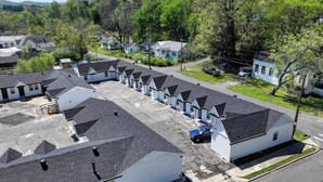 A row of single-story houses with attached garages, surrounded by trees and a clear sky. - The Boardwalk at PWC (Hot Springs)
