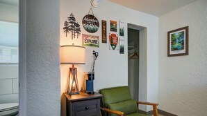 Une pièce chaleureuse avec un fauteuil vert, une lampe et différents éléments de décoration murale sur le thème du voyage.