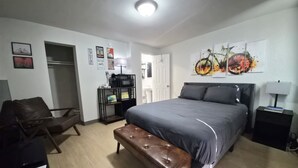 Une chambre à coucher comprenant un lit, un banc, un bureau et une étagère avec divers objets.
