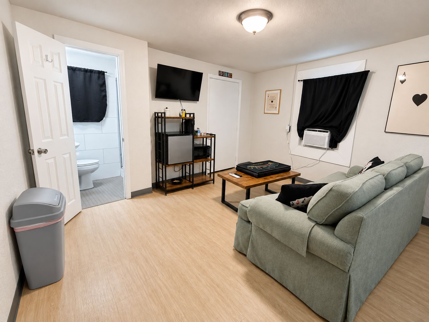 A living room with a grey sofa, a coffee table, a TV, and a small shelf unit.