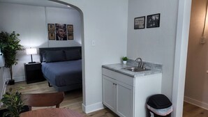 A compact room with a bed, a small kitchenette, and a dining area. - The Capone at PWC (Hot Springs)