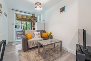 A living room with a sofa, coffee table, and a television. - Private and Beautiful 1BR Apartment near South Park,Churchill Hospital, Oxford. (Oxford)