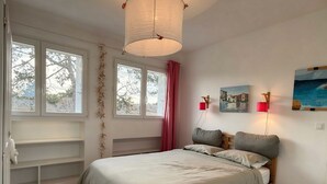 A bedroom with a bed, a window, a wall-mounted lamp, and a painting. - KerSauvage - A peaceful house on Quiberon's Côte Sauvage (Saint-Pierre-Quiberon)