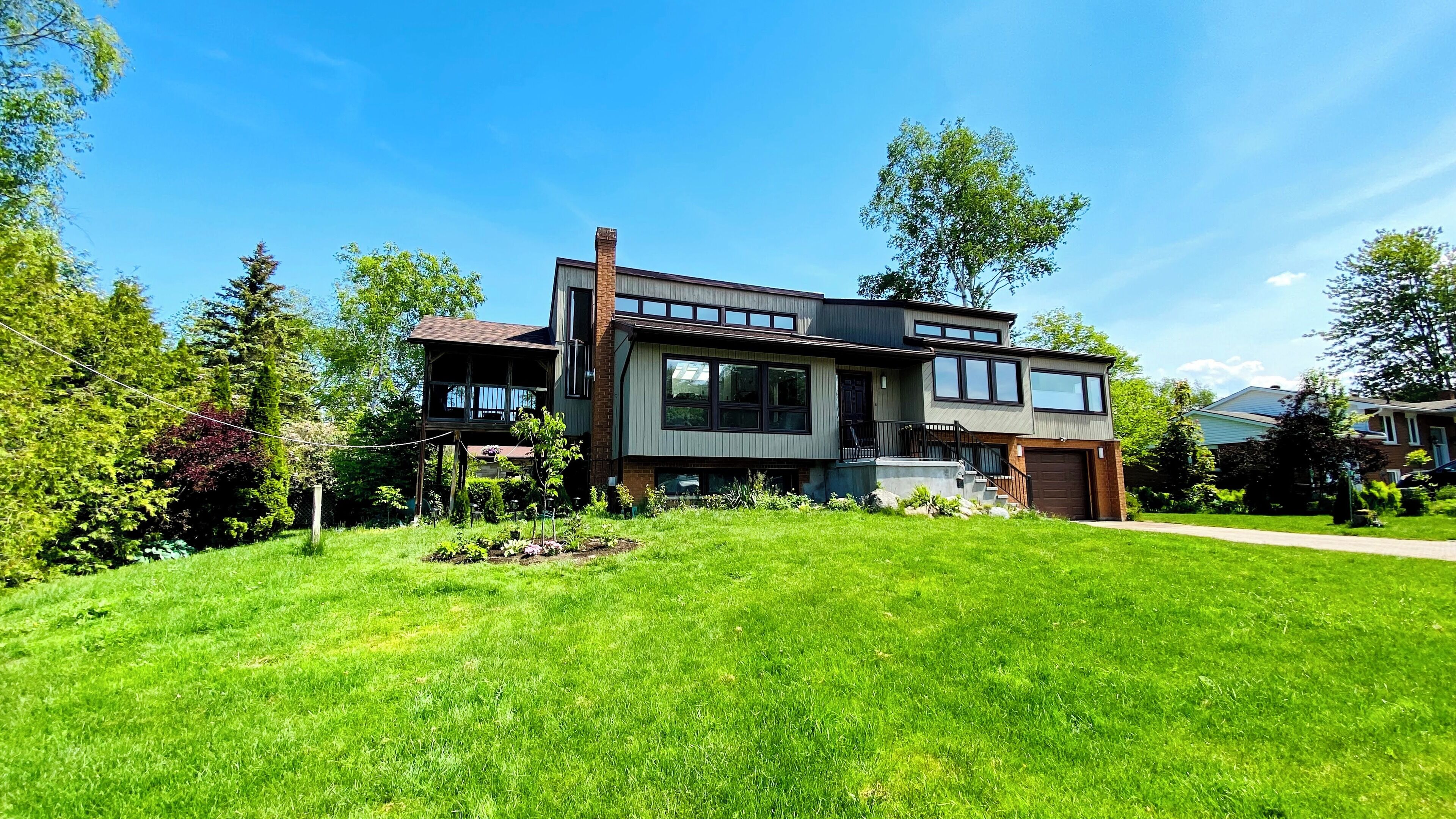 A modern two-story house with a large front lawn, a garage, and a visible staircase leading to the second floor.