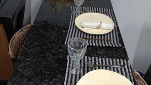 Una mesa de comedor dispuesta con platos, servilletas, cubiertos y una copa.
