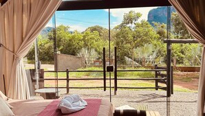 Alojamiento en tienda de campaña con cama, banco y vistas al exterior.