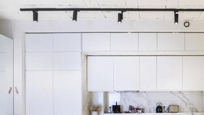 A modern kitchen with white cabinetry, a marble countertop, and a black ceiling track lighting system. - Sublime artist's loft in Montreuil ideal for families. (Montreuil)