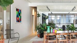 A modern office space with a wooden table, chairs, potted plants, and a colorful abstract painting. - Sublime artist's loft in Montreuil ideal for families. (Montreuil)