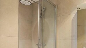 A glass-enclosed shower stall with a handheld showerhead, a white sink, and a mirror above the sink. - Sublime artist's loft in Montreuil ideal for families. (Montreuil)