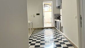 Un pasillo estrecho con suelo a cuadros que da a una puerta con vista a un patio.