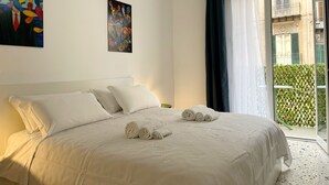 Habitación de hotel con cama, dos almohadas, un cuadro y vistas a un balcón con vegetación.