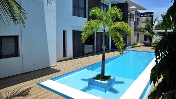 Un bâtiment moderne doté d’une piscine, de grandes fenêtres et d’un jardin bien entretenu.