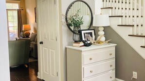 A staircase with white railings and wooden steps, leading to a landing with a white dresser and a mirror. - Masters Rental 4-bedroom house in Golf Course Community (Evans)