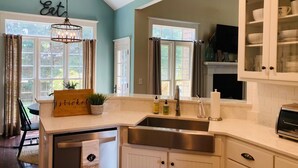 A kitchen with a central island, stainless steel appliances, and a window with curtains. - Masters Rental 4-bedroom house in Golf Course Community (Evans)