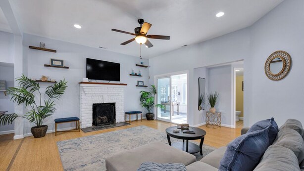 A living room with a fireplace, sofa, and television. - Bayfront backyard with a dock, 3BR, Dogs Welcome! (Norfolk)