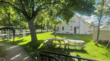 A white house with a covered patio and picnic table in a grassy yard.
