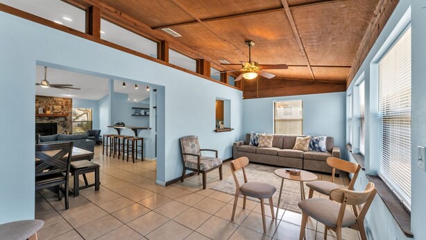 A spacious living area with a high ceiling, a stone fireplace, a sofa, and a dining table with chairs.