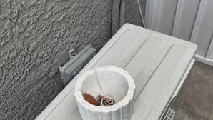 A white, rectangular, metal-framed table with a white bowl containing keys and a brown object.