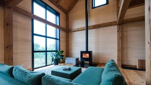 A wooden interior with a sofa, a small table, a plant, and a fireplace.