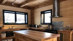 A modern kitchen with wooden cabinets, a central island, a stove, and a microwave.