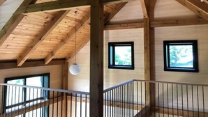 A wooden interior with high ceilings, a staircase, and windows.