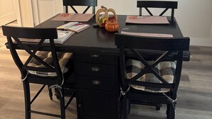 Une table à manger avec quatre chaises, un ventilateur de plafond et une porte blanche à l’arrière-plan.