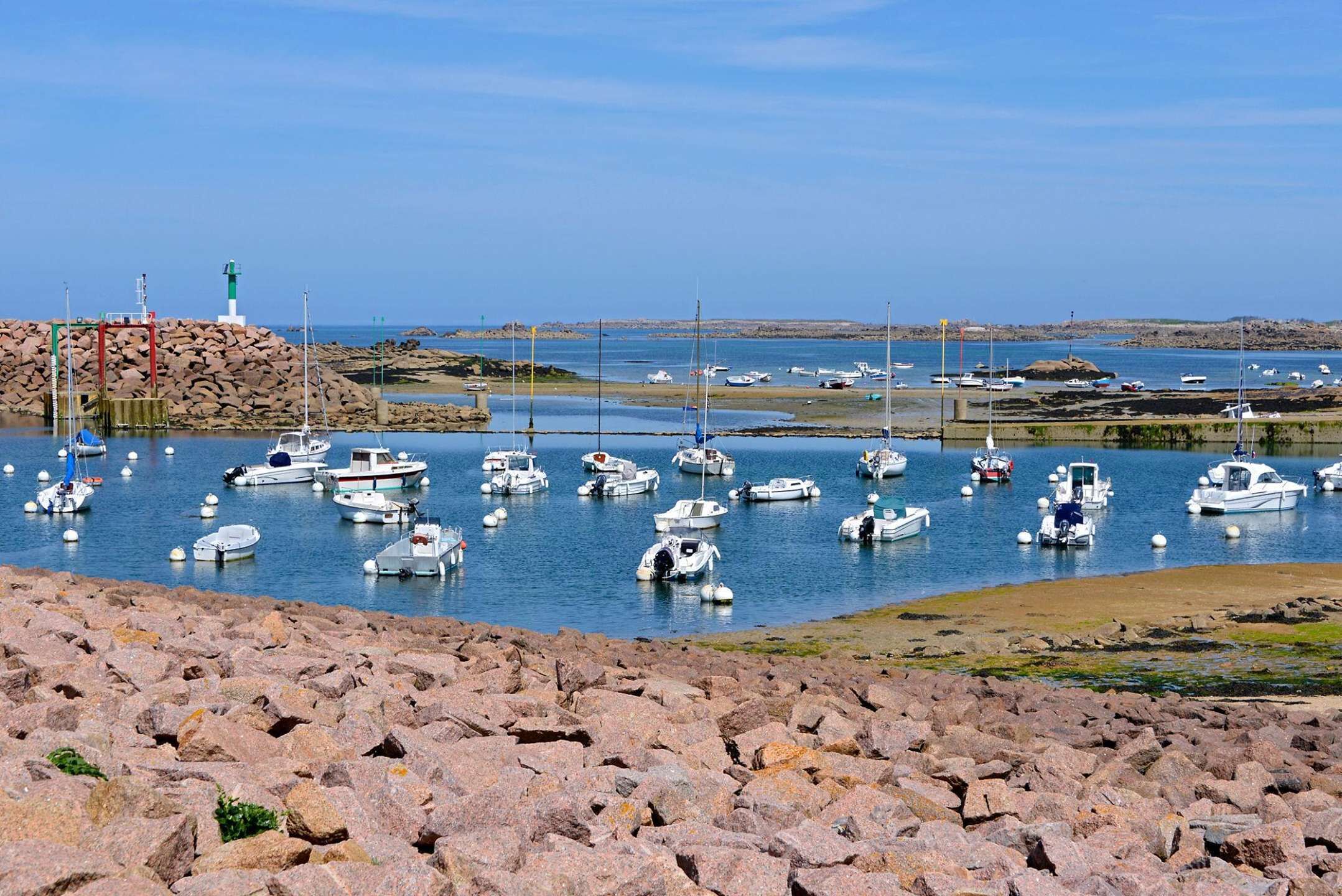 Un littoral rocheux bordé d’une marina où sont amarrés différents types de bateaux.