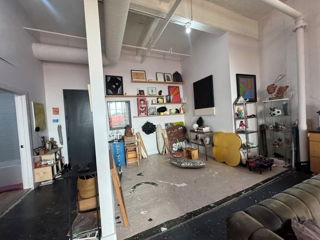 A room with a couch, shelves with various items, and a door leading to another room.