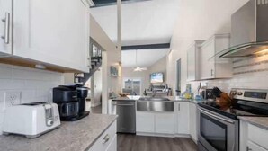Una cocina moderna con armarios blancos, electrodomésticos de acero inoxidable y encimera de granito.