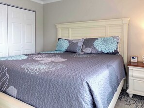 A bedroom with a large bed, a white headboard, and a nightstand with a framed picture. - Sandy Toes Retreat @ Mariner Lakes – Beautiful Condo with Easy Beach Access! (Orange Beach)