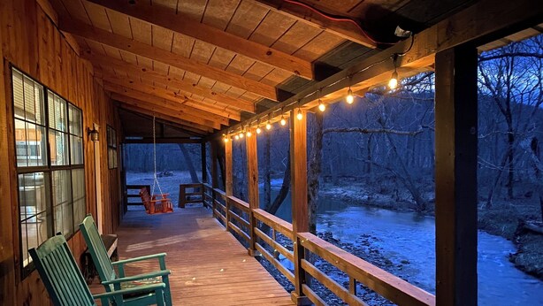 Une terrasse en bois, dotée de bancs et d’une rambarde, qui offre une vue sur une rivière.