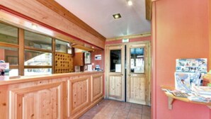 Un espace d’accueil avec des lambris en bois, un sol carrelé et un comptoir où sont exposés divers articles.