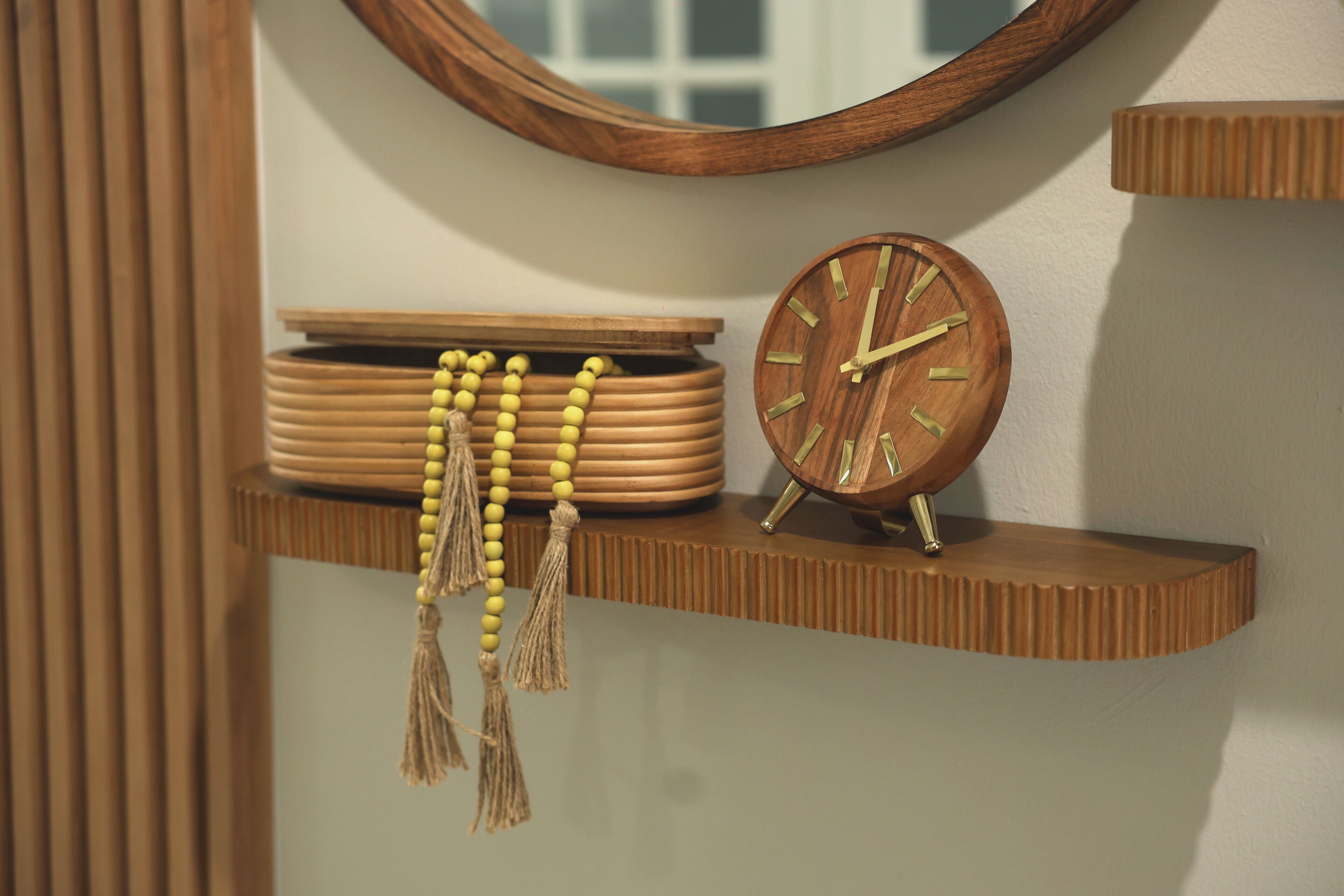 Une étagère en bois avec une horloge et des colliers ornés de perles.